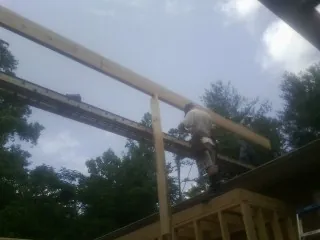 Carpenter setting a ridge beam over a new addition frame — Ice Dam Removal by Roofing Brothers in Bergheim