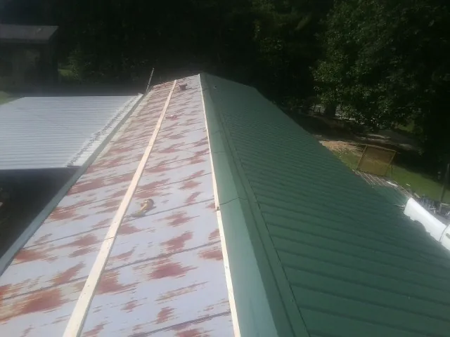 Old rusted panels beside newly installed green metal roofing — Wind Damage Roof Repair by Roofing Brothers in Bergheim