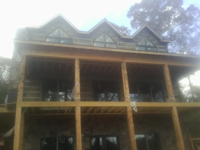 Dormers and porch framing on a large log home under construction — Roof Coating work by our crew in Bergheim