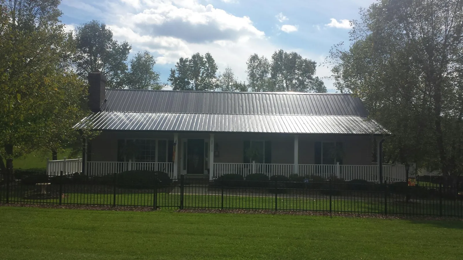 Gray metal roof on a brick ranch with a full width front porch — Gutter Guard Installation work by our crew in Bergheim